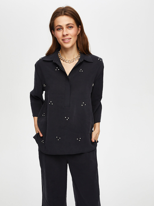 بلوزة من مودال بتصميم فائق سونميز، مزينة بنصف زر وتفاصيل حجرية، بأكمام ثلاثة أرباع.